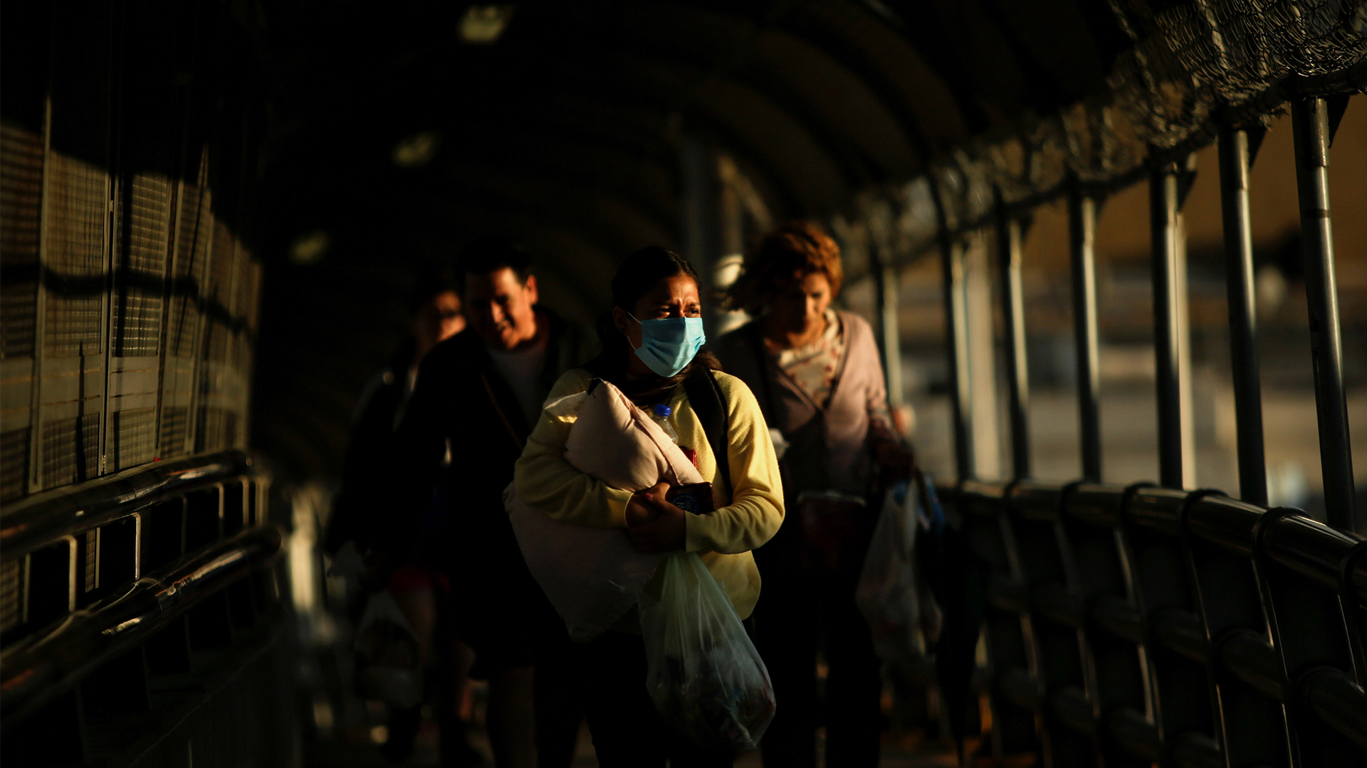 Femme portant un masque protecteur et traversant, son bébé dans les bras, le pont de la frontière internationale en route vers El Paso au Texas.